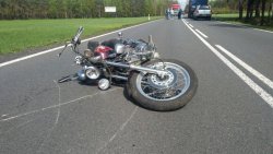 Na zdjęciu widać przewrócony motocykl, który leży na środku drogi. Pojazd przewrócony w wyniku zdarzenia drogowego