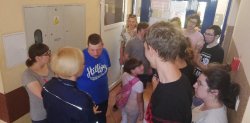 Na zdjęciu widać grupę uczniów, którzy stoją w korytarzu budynku Komendy Powiatowej Policji w Ostrzeszowie