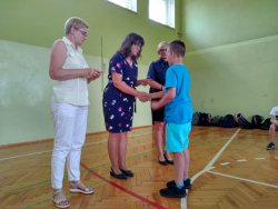 Na zdjęciu widać nauczycielkę ze Szkoły Podstawowej nr 1 w Ostrzeszowie, Dyrektora tej szkoły, uczniów siedzących twarzą do w/wymienionych osób oraz ucznia, który otrzymuje nagrodę