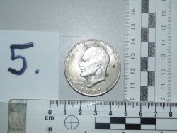 Obraz przedstawia monetę, która położony jest na biurku przy dwóch miarkach