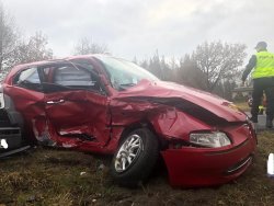 obraz przedstawia pojazd marki alfa romeo, który jest uszkodzony w wyniku wypadku, obok pojazdu stoi policjant umundurowany