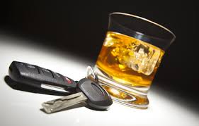 Zdjęcie przedstawia szklankę z płynem oraz kluczyki do samochodu