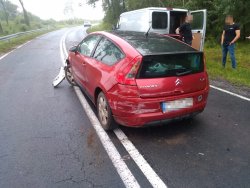 Na zdjęciu widać łuk drogi oraz ustawiony na jezdni pojazd marki Citroen z widocznymi uszkodzeniami powstałymi w wyniku zdarzenia drogowego.